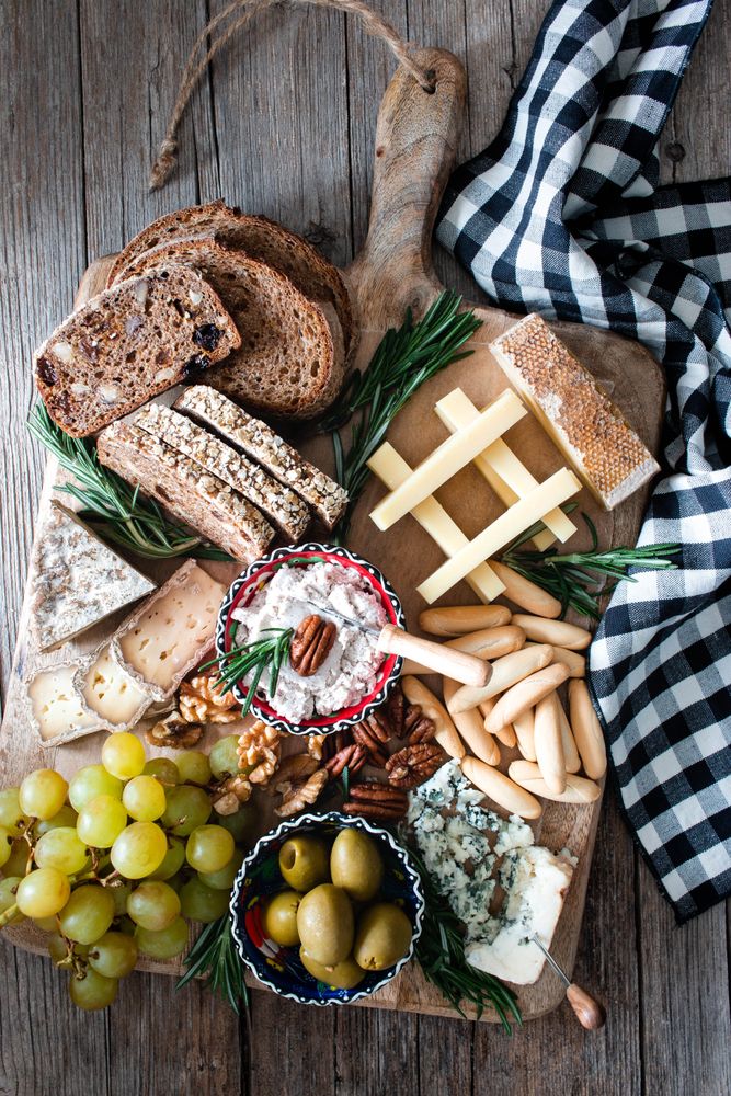 Bred, cheese, olives and grapes on wooden board