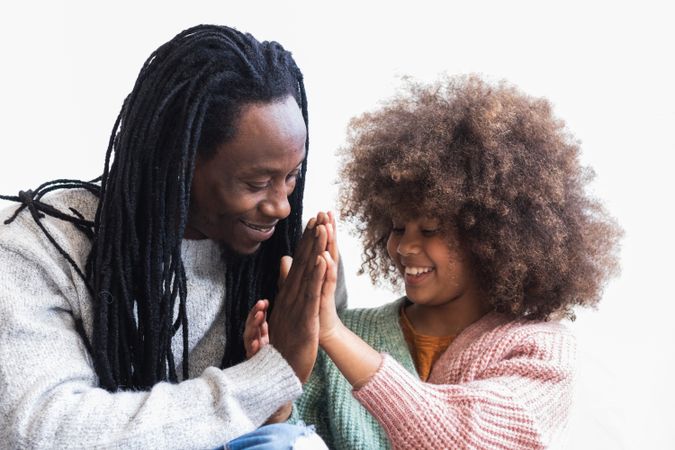 Delighted Black man cuddling with daughter