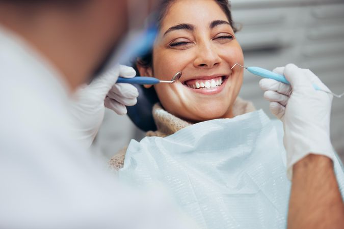 Female patient wearing paper bib as dentist works on her teeth