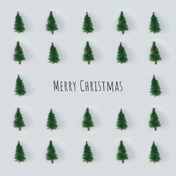 Christmas trees arranged on gray background with “Merry Christmas”