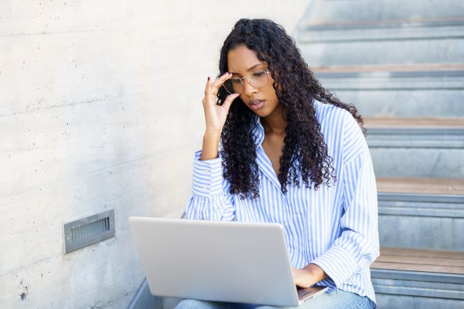 A focused young woman diligently working on her laptop in a modern office environment