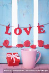 Red gift, pink coffee cup and the word love spelled out hanging on a banner 5qLgY0