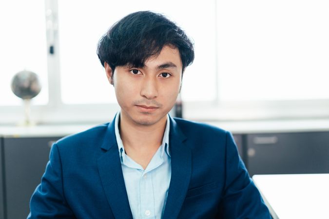 Serious Asian male in suit in his office