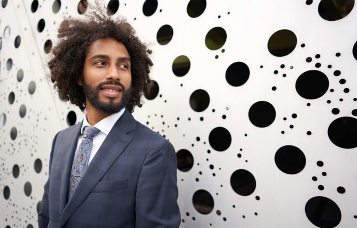 Cheerful entrepreneur standing next to wall with holes