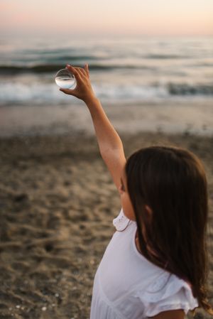 Girl playing with glass ball on seaside