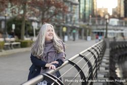 Smiling woman leaning on a railing outside 5nEkn0