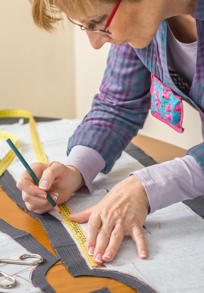 Dressmaker drawing tailor pattern on the table