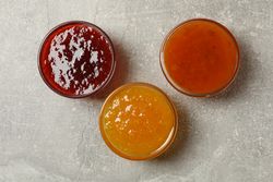 Bowls with jam on gray background, top view