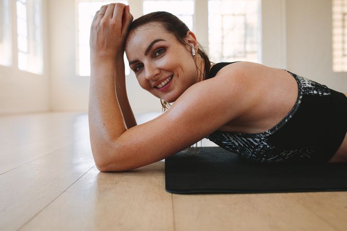 Tired woman resting after intense workout on yoga mat
