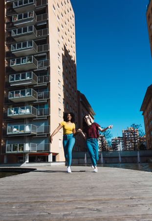 Two female friends skipping in town