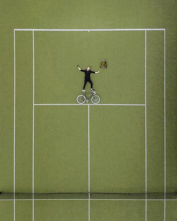 Aerial view of man laying beside a bicycle on tennis court