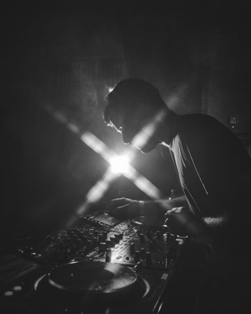 London, England, United Kingdom - Nov 9, 2022: B&W shot of side view of man DJ-ing with flare