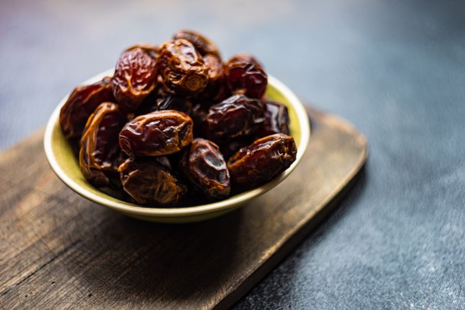 Organic dates in a yellow bowl on dark table