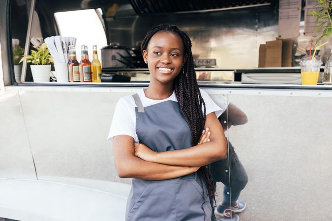 Black woman in apron outside her silver food truck