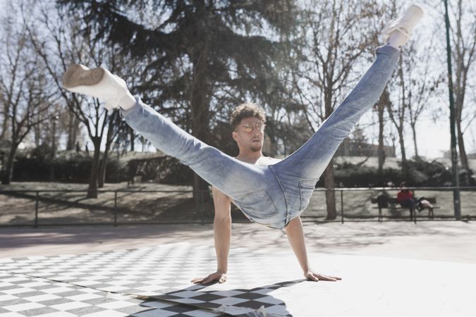 Shirtless man dancing break dance in park