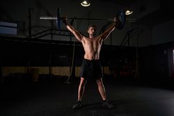 Muscular concentrated athlete with barbell with weights in strai