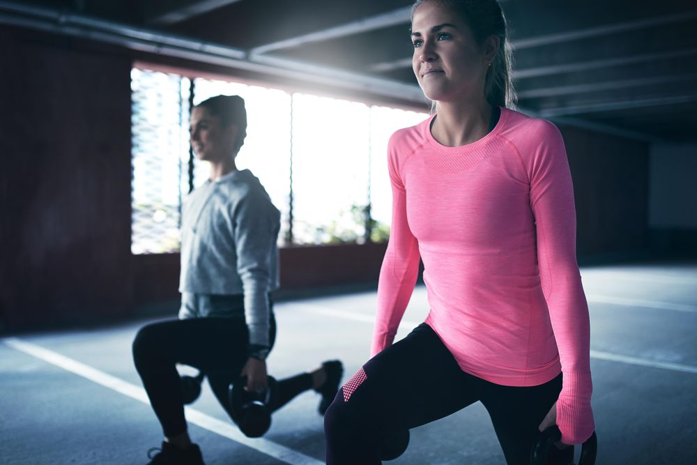 Two woman doing lunges in car park