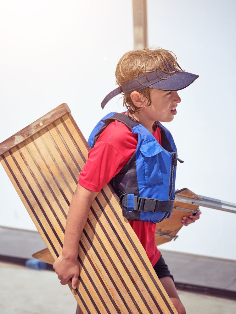 Boy with wooden board and blue life jacket