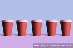Single row of disposable coffee cups on blue and purple background 0y9lq0