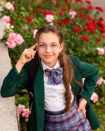 Girl standing surrounded by blooming flowers.