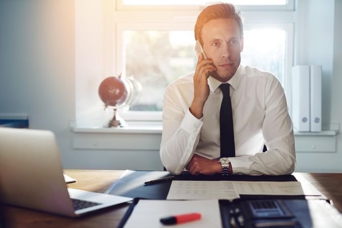 Man in shirt and tie on cellphone in office