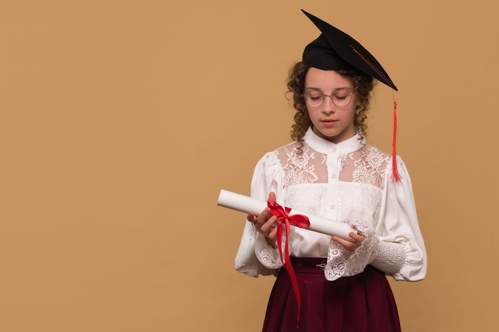 A young graduate looking down at diploma scroll