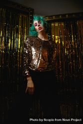 Woman with green hair and golden jacket standing beside curtain 4jwl9b