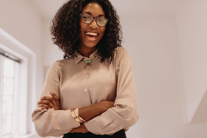 Happy Black woman in blouse with her arms crossed
