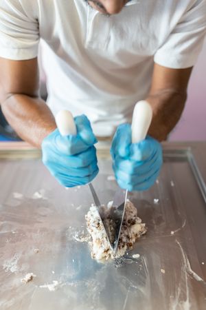 A worker is using spatulas to prepare a roll on a rolled ice cream machine