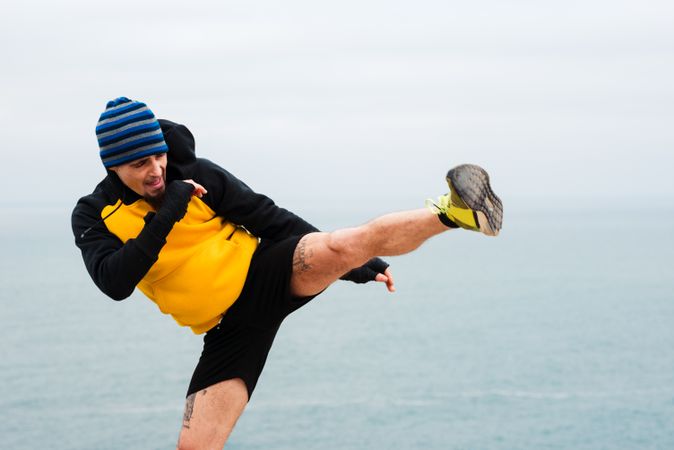 Kickboxer training on cliff near sea