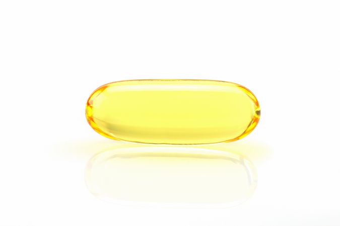 Close up golden color fish oil supplement in soft gel capsule