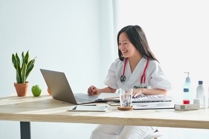 Content Asian medic having video call during telemedicine consul