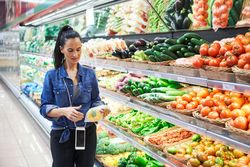 Female customer in supermarket against vegetables