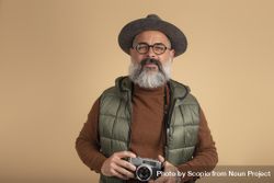 Bearded man holding a camera standing against yellow background 5QX2V0