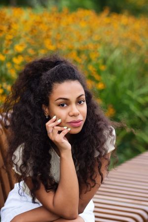 Portrait of Black female relaxing on bench in front of flowers