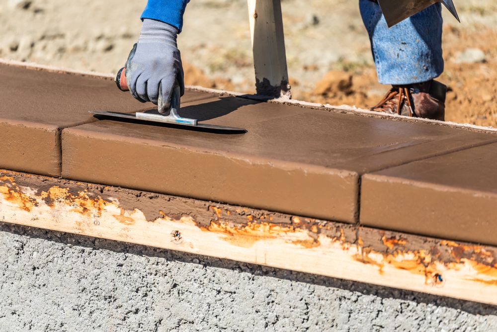 Construction Worker Using Trowel On Wet Cement Forming Coping Around New Pool