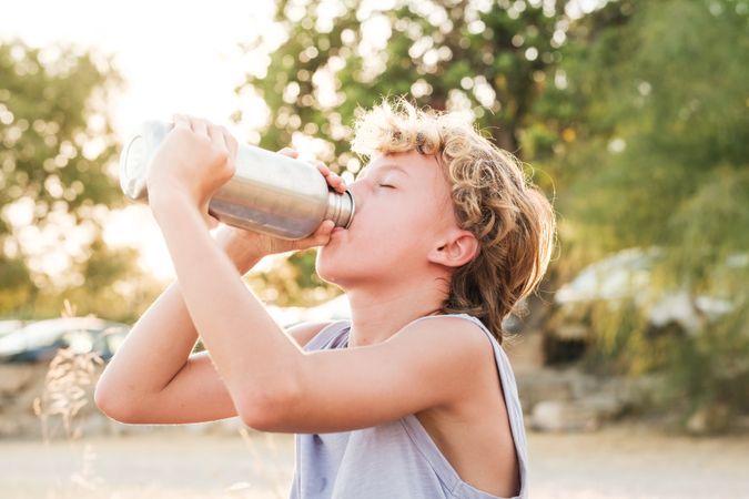 Fit boy drinking water from bottle after workout