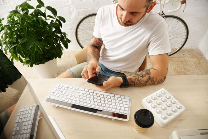 Tattooed freelancer in blank t-shirt in bright workspace