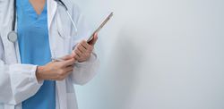 Doctor standing in light hospital room with copy space, wide