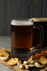 Beer and snacks on gray table against wooden background