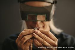 Woman goldsmith examining sliver designer ring using magnifying glass 0vyxdb