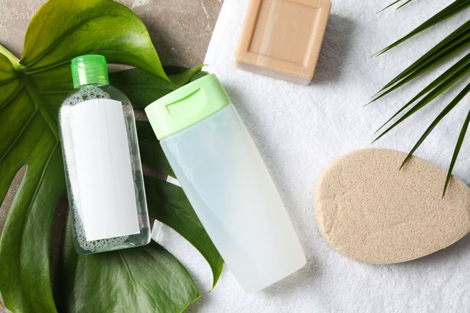 Palm leaves, soap, sponge, shower gel, shampoo and towel, top view