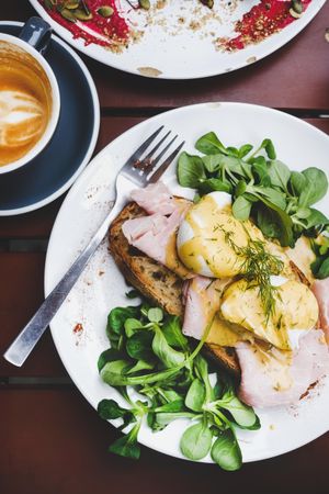 Eggs Benedict with greens, coffee, top view