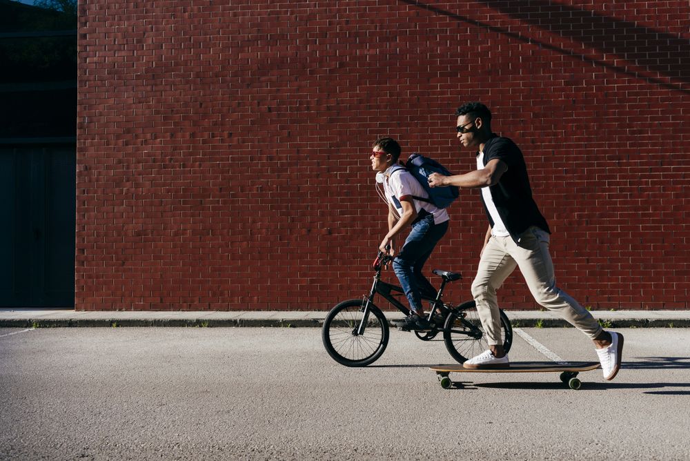 Young Black men riding bicycle and skateboard