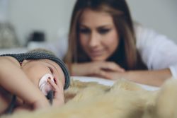 Baby sleeping on a blanket while her mother looks