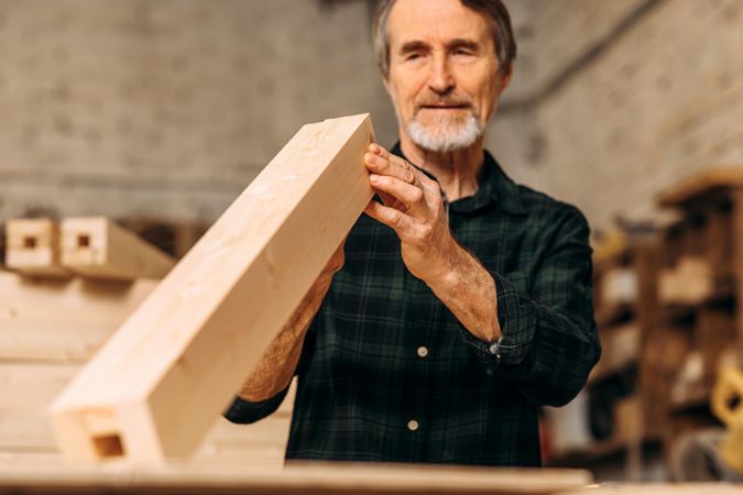 Mature man with block of wood in workshop