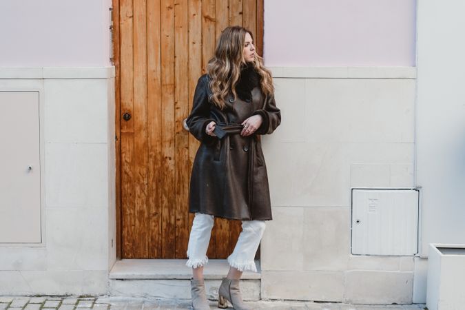 Stylish woman standing near brown door