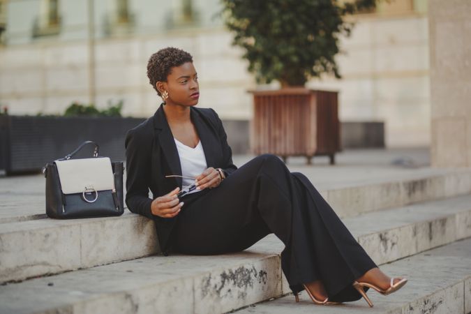 Stylish Black woman with handbag and sunglasses on steps