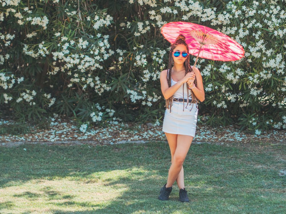 Fit young female with umbrella standing near blooming trees