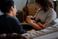 Loving female couple rocking baby to sleep on sofa